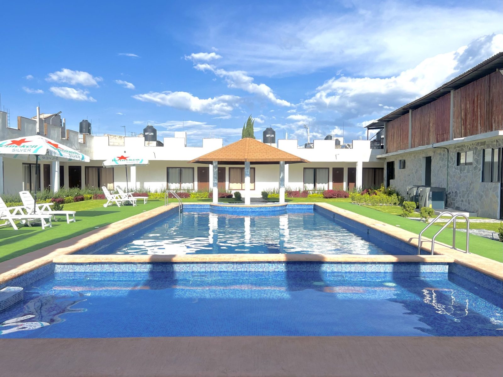 Alberca climatizada al aire libre del complejo, con camastros y habitaciones alrededor